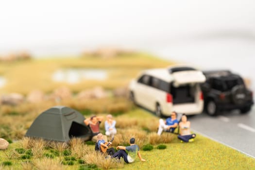 Miniature campers on grassland with vehicles on the road
