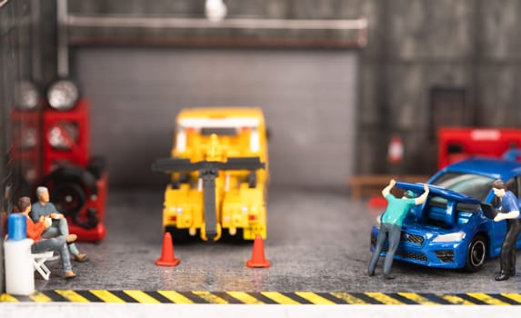 Miniature customers sitting and waiting while the mechanic checking on engine and technician is doing a diagnostic on the car