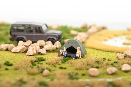 Miniature man playing guitar with his friend at campsite