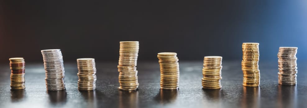 Towers of the coins on the black background. Concept of the earnings, finance and economy.