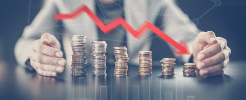 Woman sitting at the table and holding hands around the towers of the coins. Concept of the global business and money savings.