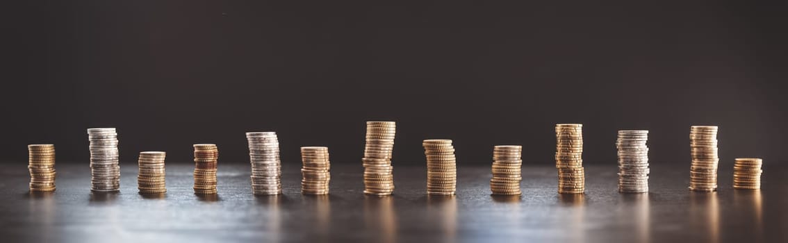 Towers of the coins on the black background. Concept of the earnings, finance and economy.