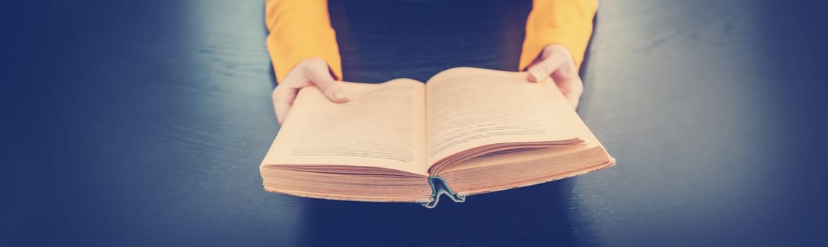 Woman sitting indoors and reading a vintage book. Concept of wisdom and knowledges.