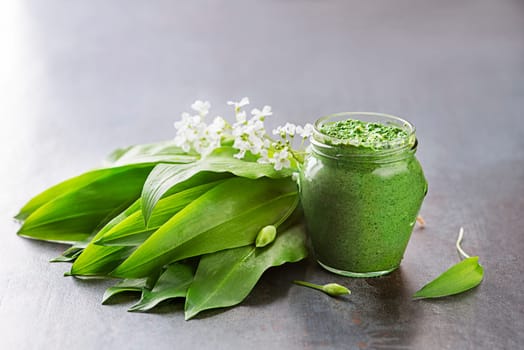 Fresh ramson or wild garlic pesto in glass jar close up. Healthy spring food concept