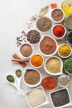 Colorful herbs and spices for cooking meal. Indian and asian spices On white stone background. Top view.