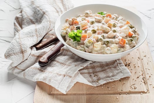 Bowl of russian salad olivier french salad with vegetables and egg dressed with mayonnaise on white table close up