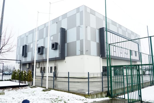 Sremska Mitrovica, Serbia, January 27, 2023. City swimming pool building. Pinky Swimming Pool, next to the Pinky Sports Centre. Modern sports building, gray and white ventilated facade. Snow in winter