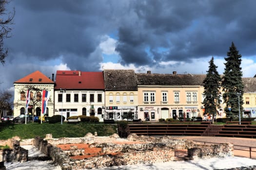 Sremska Mitrovica, Serbia, March 16, 2023 Zitni trg historical square. Ancient multi-colored buildings and excavations of Roman times. Cultural heritage. Dramatic sky. Excavations of Roman chambers