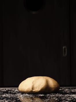 Floured organic yeast dough lies on the kitchen work surface, Dough ball ready for further processing.