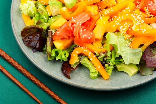 Tasty salad with salmon, mango, sesame avocado and pepper. Healthy eating, space for text. Food and chopsticks