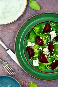 Homemade salad with beets, blue cheese, greens and pine nuts on the plate. Proper nutrition.