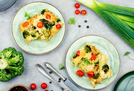 Appetizing potato gratin with broccoli and tomatoes on a plate. Top view.