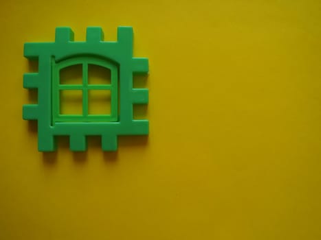 Multicolored plastic kids constructor on yellow background. Colored children's bricks for construction. Flat lay top view copy space. Plastic building blocks background. Developing toys, game