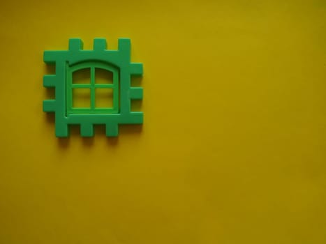 Multicolored plastic kids constructor on yellow background. Colored children's bricks for construction. Flat lay top view copy space. Plastic building blocks background. Developing toys, game