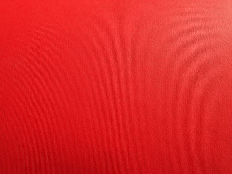 Abstract red background with texture. Close-up of paper surface with light and color gradient. Side lighting. Bright crimson backdrop.