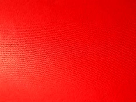 Abstract red background with texture. Close-up of paper surface with light and color gradient. Side lighting. Bright crimson backdrop.