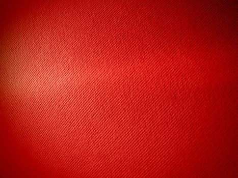 Abstract red background with texture. Close-up of paper surface with light and color gradient. Side lighting. Bright crimson backdrop.