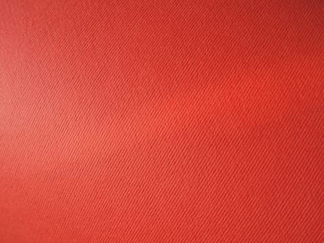 Abstract red background with texture. Close-up of paper surface with light and color gradient. Side lighting. Bright crimson backdrop.