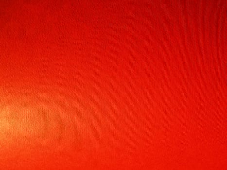 Abstract red background with texture. Close-up of paper surface with light and color gradient. Side lighting. Bright crimson backdrop.