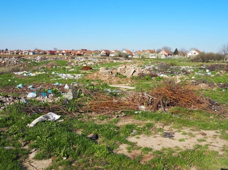 garbage dump near the village. Chaotic unofficial dump. Plastic, bags, paper, glass, biological waste. Green grass next to dirt. Ecological catastrophy