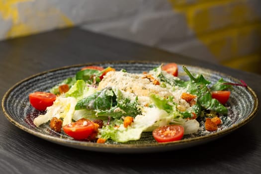 Caesar salad, in dark clay plate on wooden table