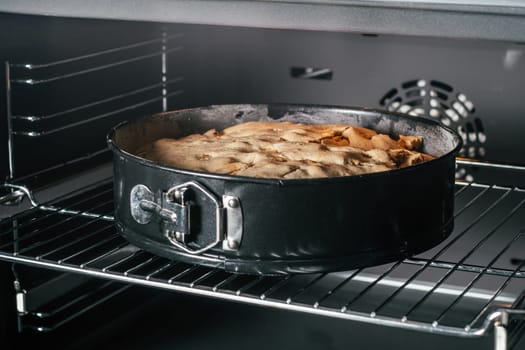 Baking dish with apple pie stands in black oven. Homemade seasonal bakery. Cooking in process
