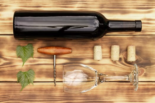 Wine glass, corkscrew, corks, wine bottles, grapevine on rustic burnt wooden background. Top view, copy space