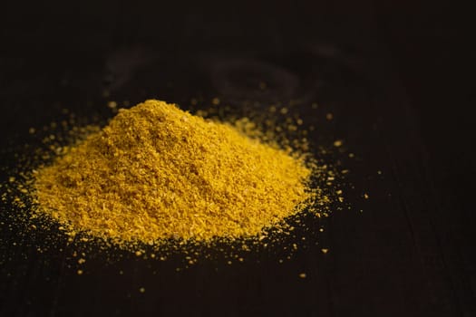 A slide of yellow turmeric or curry spice powder on a black wooden surface, copy space