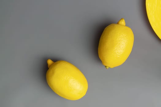 Yellow lemons on gray background. Colors of the Year 2021 Illuminating and Ultimate gray, flat lay, copy space