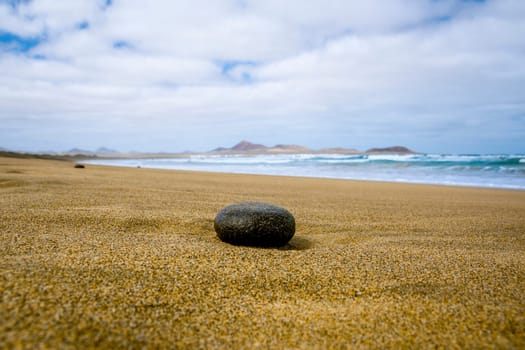 Empty beach with black stone in the foreground