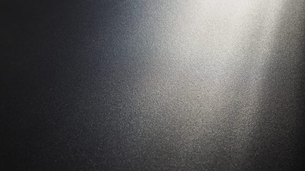 White bokeh and beam on a black background. Blurred glow from above on a dark surface. Night or space theme. Bokeh for the holiday. Abstract background. Glare, ray and light shine from above