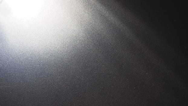 White bokeh and beam on a black background. Blurred glow from above on a dark surface. Night or space theme. Bokeh for the holiday. Abstract background. Glare, ray and light shine from above
