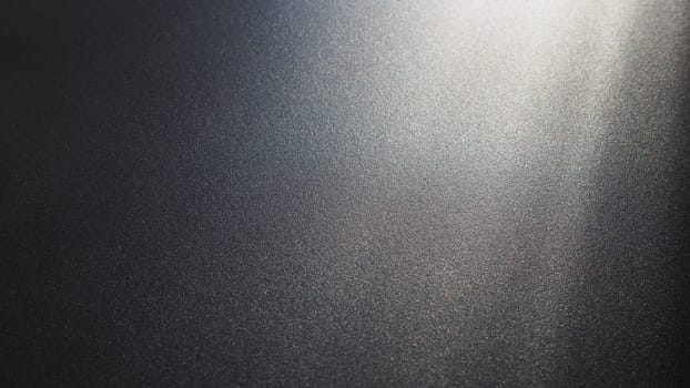 White bokeh and beam on a black background. Blurred glow from above on a dark surface. Night or space theme. Bokeh for the holiday. Abstract background. Glare, ray and light shine from above