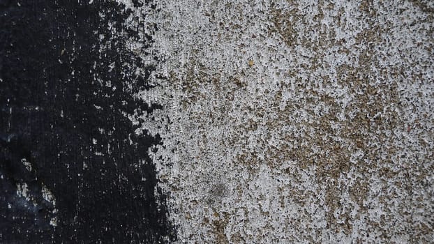 Concrete wall with black and white stripe of paint. Carelessly brushed parts, translucent gray plaster through the applied oil paint. Grunge background with empty space. Copy space.