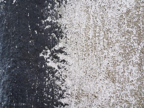 Concrete wall with black and white stripe of paint. Carelessly brushed parts, translucent gray plaster through the applied oil paint. Grunge background with empty space. Copy space.