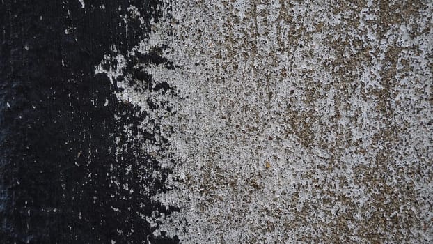 Concrete wall with black and white stripe of paint. Carelessly brushed parts, translucent gray plaster through the applied oil paint. Grunge background with empty space. Copy space.