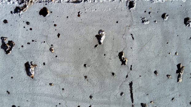Concrete wall with concentric damage of large radius. Potholes, tubercles and defects. Grey colour. Planet surface concept. Concrete wall with a worn surface, potholes, bulges and small spots