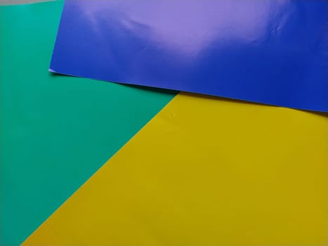 Blue, green and yellow paper is stacked on top of each other. Colorful background. Blue background with pink gradient. Sheets of colored paper for creativity.