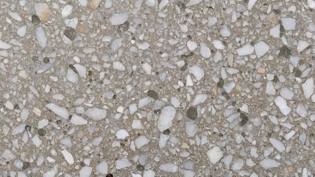 Concrete surface with multi-colored blotches of small stones. Light beige tone. Wall of a building or concrete slab. Close-up. Pockmarked cement surface. Interior or exterior finish option.