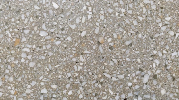 Concrete surface with multi-colored blotches of small stones. Light beige tone. Wall of a building or concrete slab. Close-up. Pockmarked cement surface. Interior or exterior finish option.
