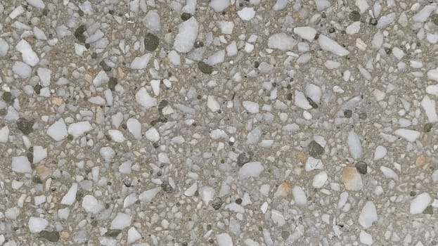 Concrete surface with multi-colored blotches of small stones. Light beige tone. Wall of a building or concrete slab. Close-up. Pockmarked cement surface. Interior or exterior finish option.
