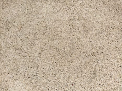 Concrete surface with multi-colored blotches of small stones. Light beige tone. Wall of a building or concrete slab. Close-up. Pockmarked cement surface. Interior or exterior finish option.