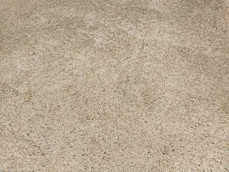 Concrete surface with multi-colored blotches of small stones. Light beige tone. Wall of a building or concrete slab. Close-up. Pockmarked cement surface. Interior option.