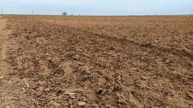 Freshly plowed field. Arable land with fertile soil for planting wheat. Rural landscape in Serbia, Balkans, namely Fruska Gora from Sremska Mitrovica. Furrows and pits. Preparatory agricultural work.