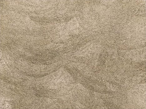 Concrete surface with multi-colored blotches of small stones. Light beige tone. Wall of a building or concrete slab. Close-up. Pockmarked cement surface. Interior or exterior finish option.