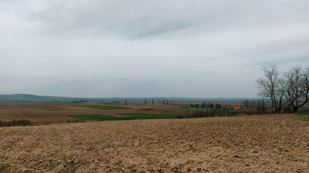Freshly plowed field. Arable land with fertile soil for planting wheat. Rural landscape in Serbia, Balkans, namely Fruska Gora from Sremska Mitrovica. Furrows and pits. Preparatory agricultural work.