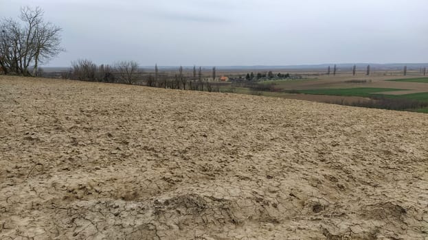 Freshly plowed field. Arable land with fertile soil for planting wheat. Rural landscape in Serbia, Balkans, namely Fruska Gora from Sremska Mitrovica. Furrows and pits. Preparatory agricultural work.