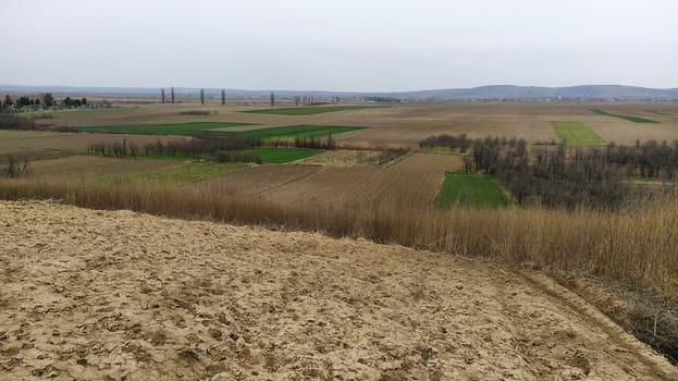 Freshly plowed field. Arable land with fertile soil for planting wheat. Rural landscape in Serbia, Balkans, namely Fruska Gora from Sremska Mitrovica. Furrows and pits. Preparatory agricultural work.