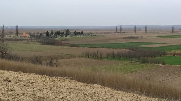 Freshly plowed field. Arable land with fertile soil for planting wheat. Rural landscape in Serbia, Balkans, namely Fruska Gora from Sremska Mitrovica. Furrows and pits. Preparatory agricultural work.