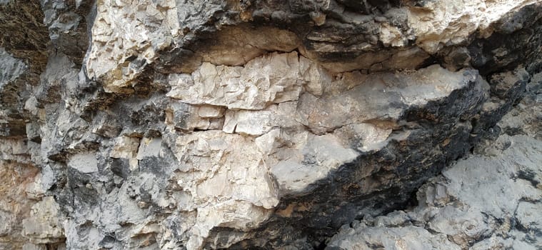 stone rock closeup in Sarajevo, Bosnia and Herzegovina. Ancient frozen lava. Layers and strata of rocks. Mountain after a guided explosion to lay the road. Texture of the stone. Gray and beige colors.
